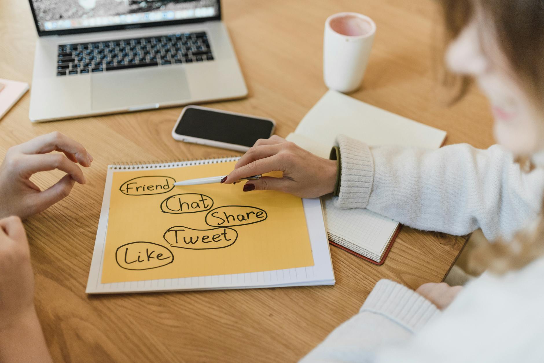 Robot hand writing on a tablet next to a human hand writing on paper, symbolizing AI content writing vs human content for digital marketing